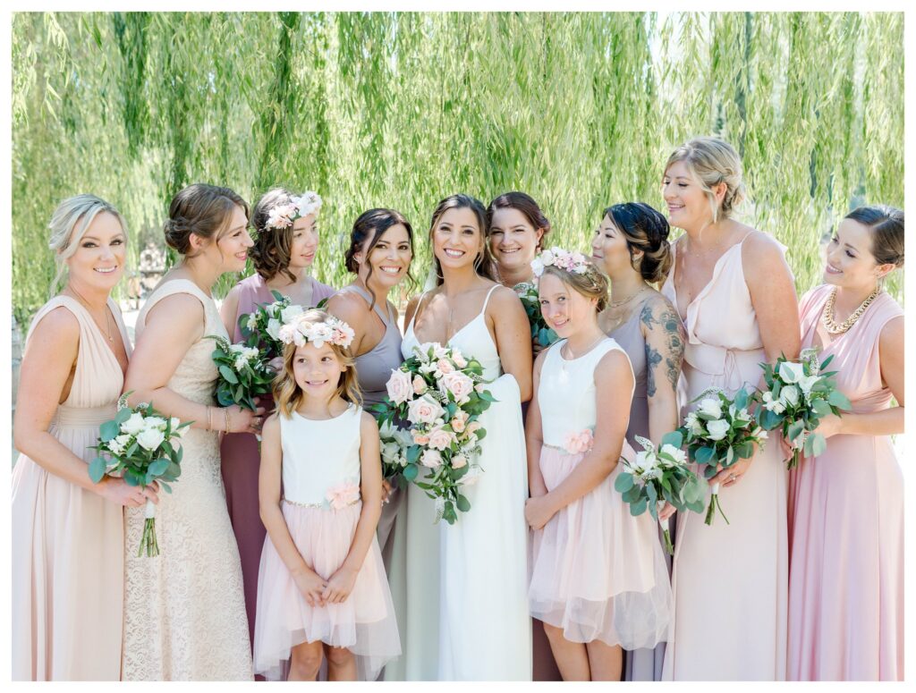 bridesmaids smile in pink dresses under the vines at Terra Mia vineyard on a summer wedding day in Pas Robles ca.