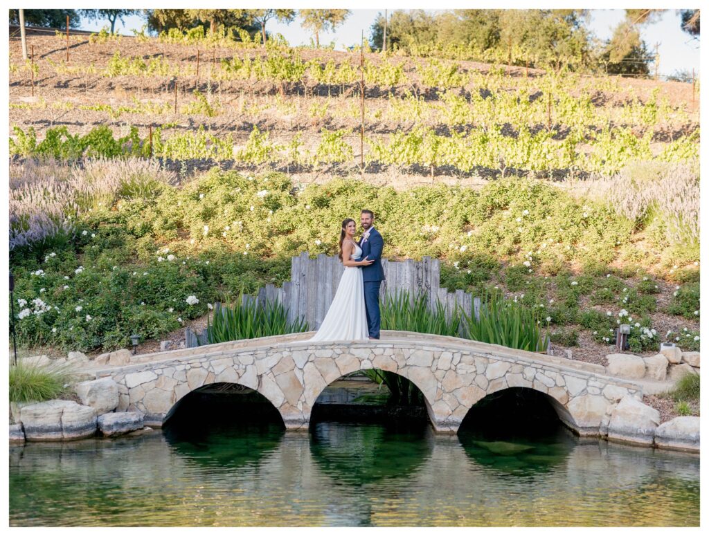 A bride and groom walk over the bridge at TERRA MIA Vineyards during this romantic moment on their relaxed and affordable wedding day.