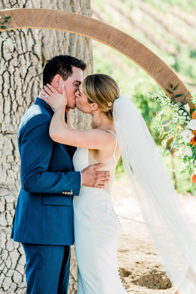 a bride and Groom kiss during their Ellas Vineyard wedding ceremony.