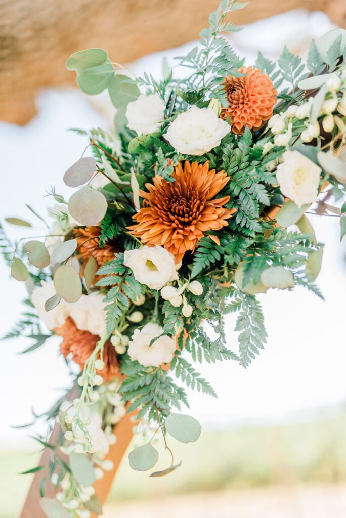 A colorful bouquet of summertime flowers in orange and green during a summer wedding at Ellas Vineyard. Period 