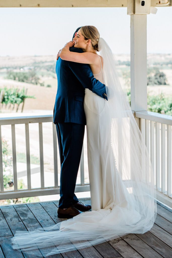 A bride and groom embrace their first on their wedding day at the farmhouse in Ellas Vineyard