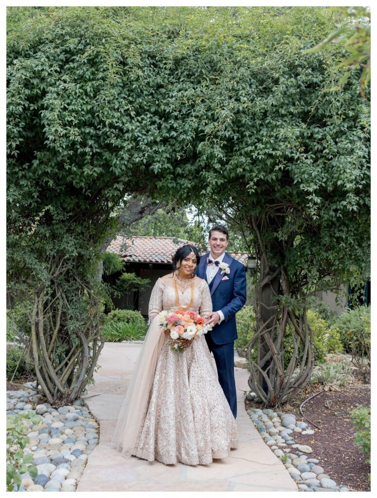 Couple smiling under greenery arch – Willow and Oak Indian wedding – Leana Myra Photography