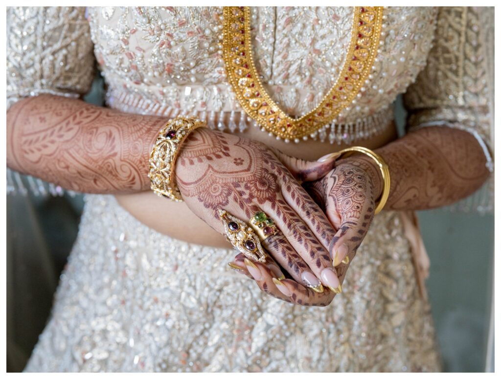 Detail of bride's intricate henna-decorated hands and romantic dip kiss with groom at sunset in Paso Robles, captured by Leana Myra Photography.