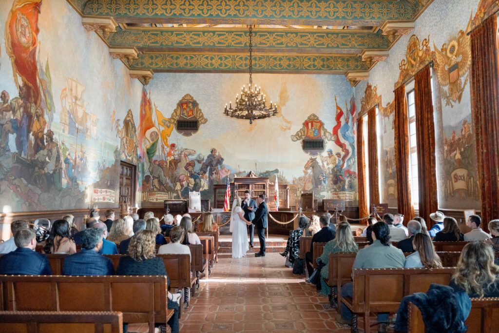 a wedding ceremony in the mural room at the santa barbara courthouse