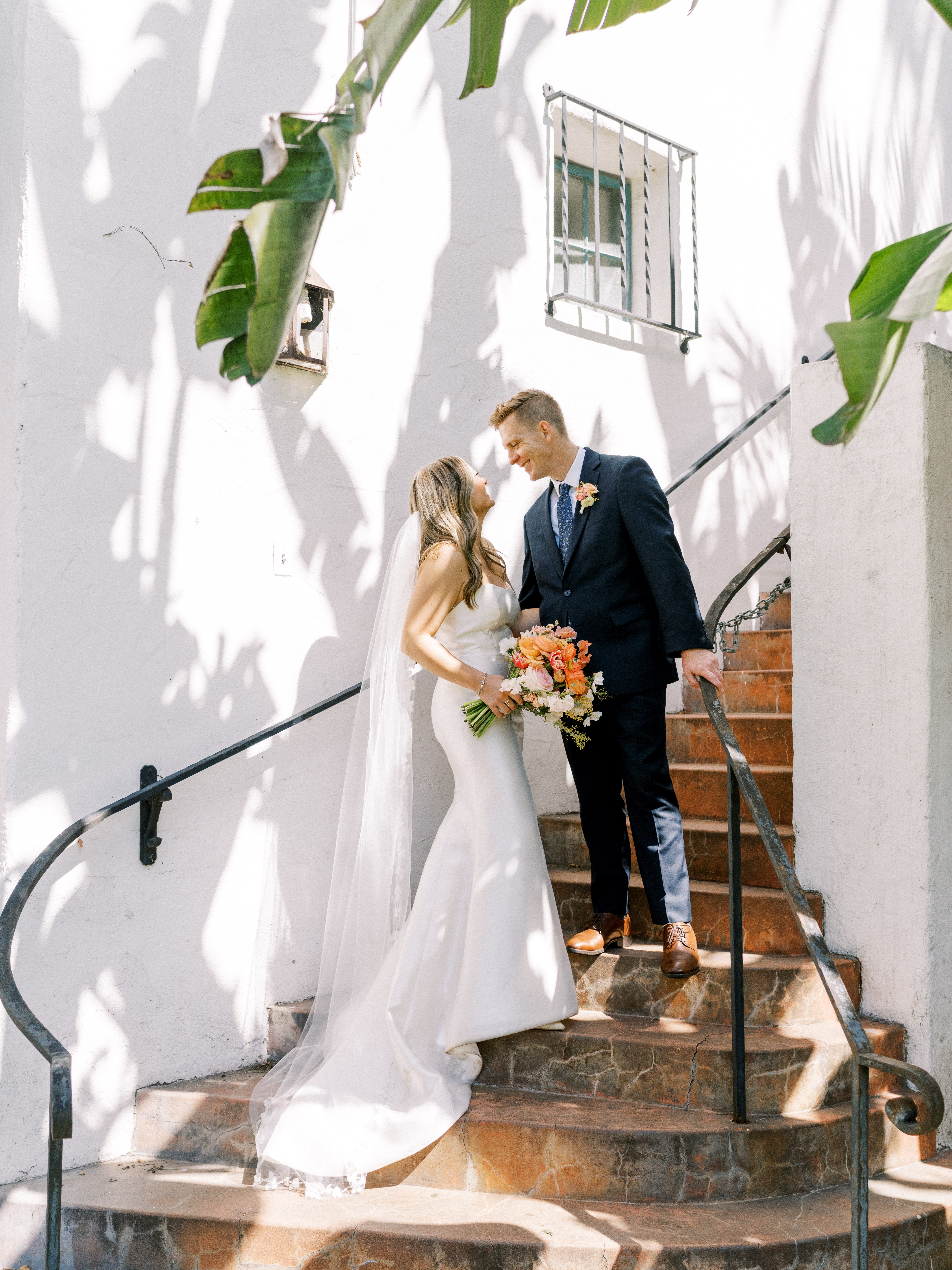 Bride and groom wearing elegant editorial attire pose on steps at the santa barbara courthouse
