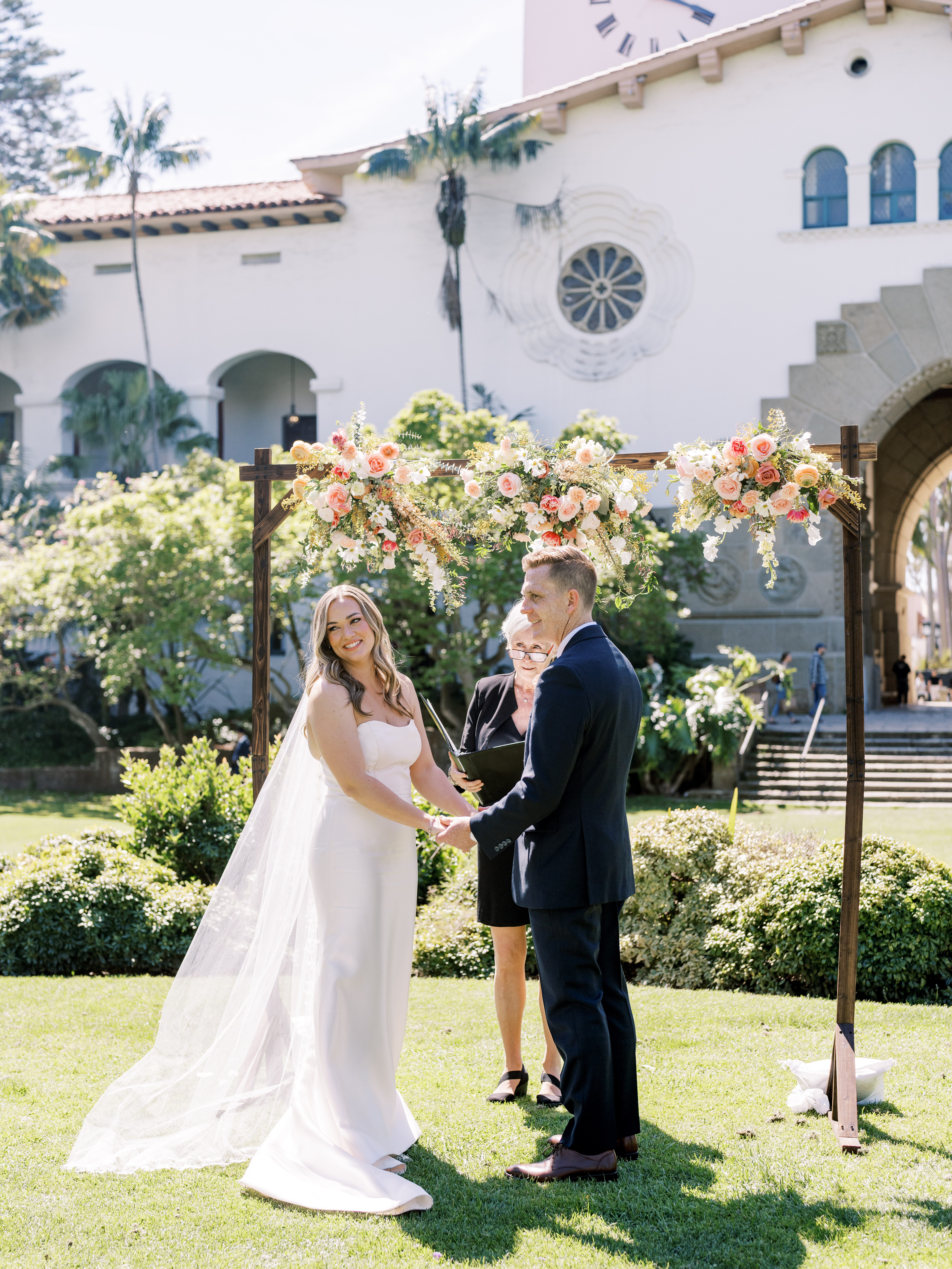 Wedding ceremony on the lawn at the Santa Barbara Courthouse with floral arch