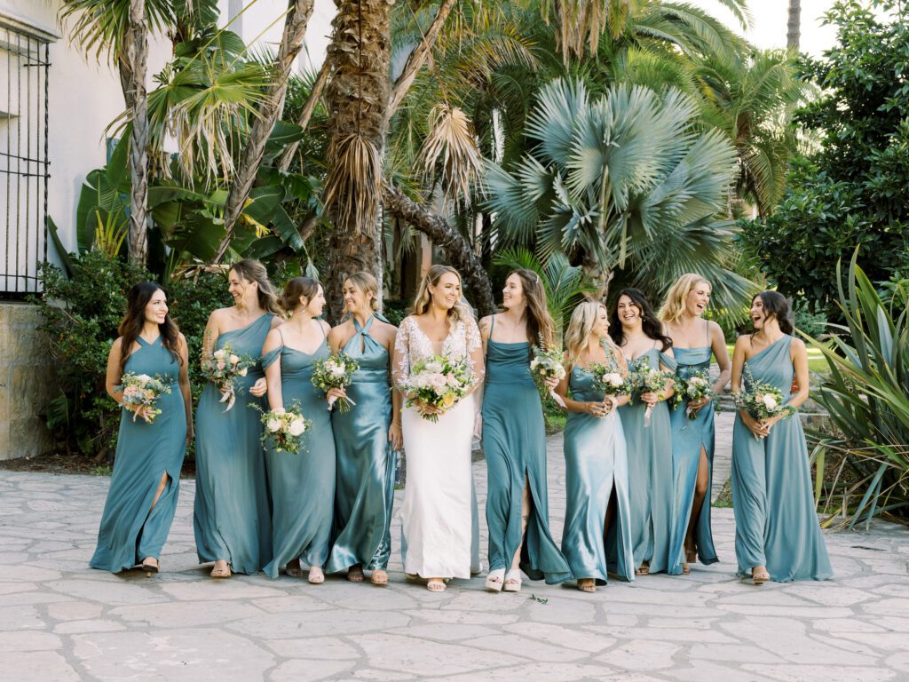 Bridesmaids walk together in green dresses at the Santa Barbara Courthouse