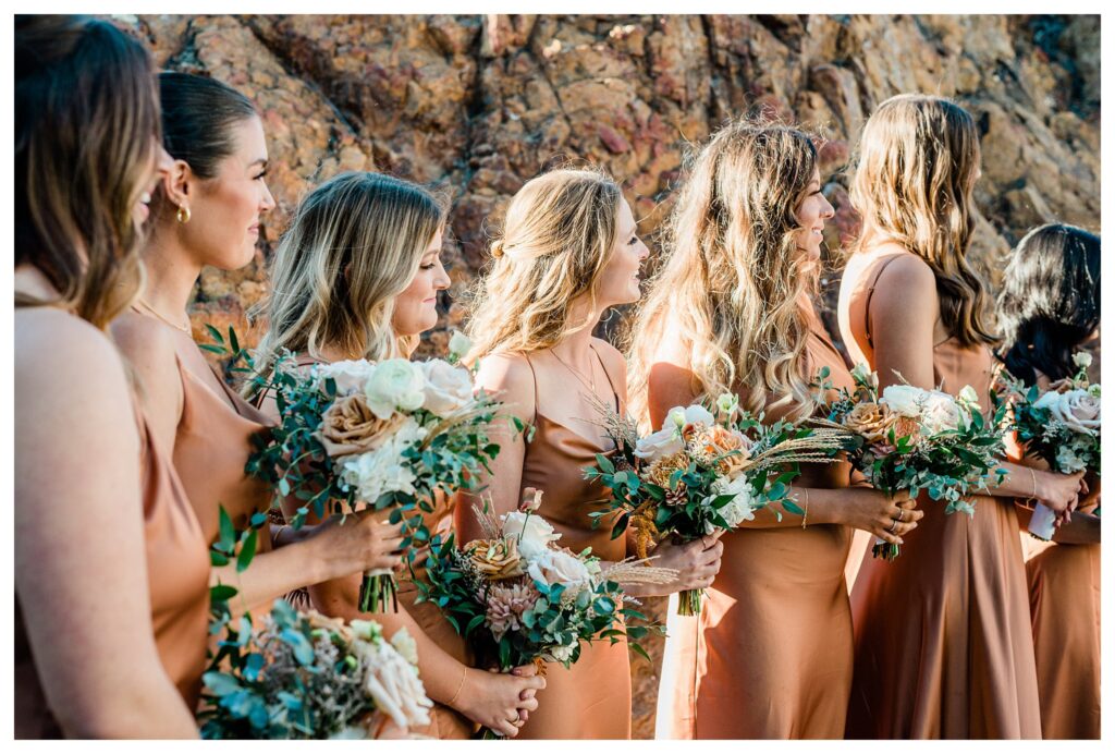 Bridesmaids at ceremony with boho triangle arch and fall florals at the Slo brew Rock.