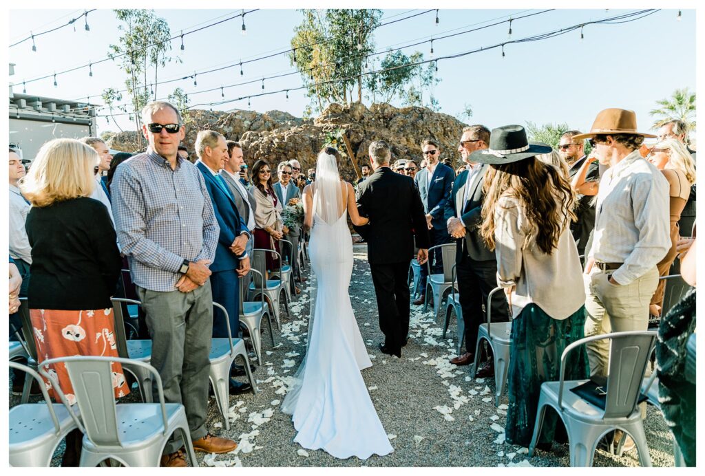 Slo brew Rock wedding ceremony, bride and groom in front of a boho style triangle ceremony arch and warm fall colors in san luis obispo.
