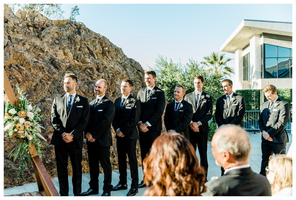 Slo brew Rock wedding ceremony, groomsmen in front of a boho style triangle ceremony arch and warm fall colors in san luis obispo.