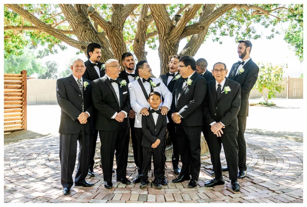 Groomsmen in black tuxes laughing  luxury wedding at Maravilla gardens in Camarillo, by a light and airy wedding photographer. 