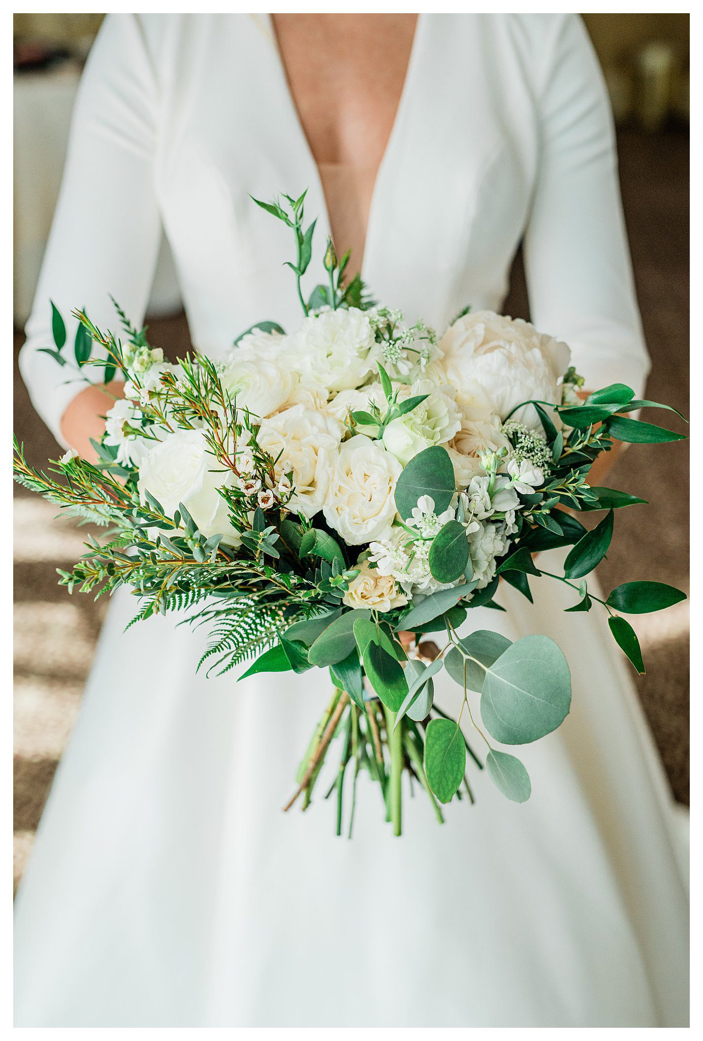 Bride holding up green and white bouquet of wedding flowers.