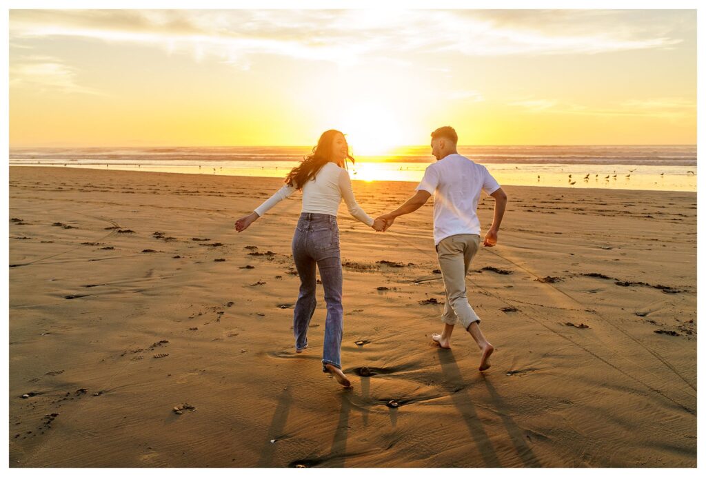 An engaged couple runs through the sunset on the beach for whimsical and candid engagement. Photos from a wedding photographer in San Luis Obispo.