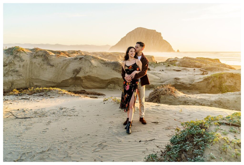 San Luis Obispo engagement session locations like Morro Bay beach are popular for their beauty, such as in this picture of an engaged couple embracing in the sunset.