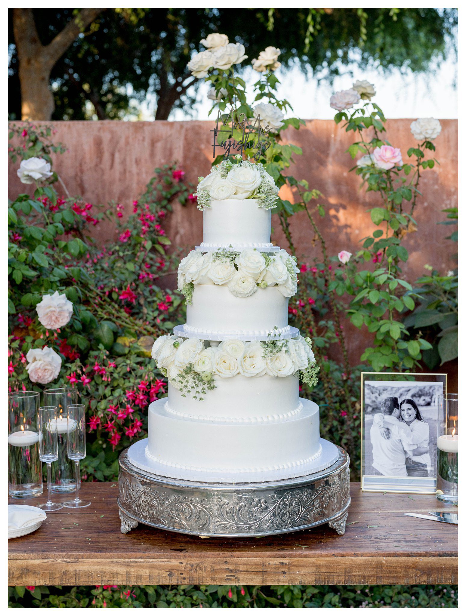 Elegant tiered cake with white roses in garden setting at Maravilla Gardens in Camarillo.

