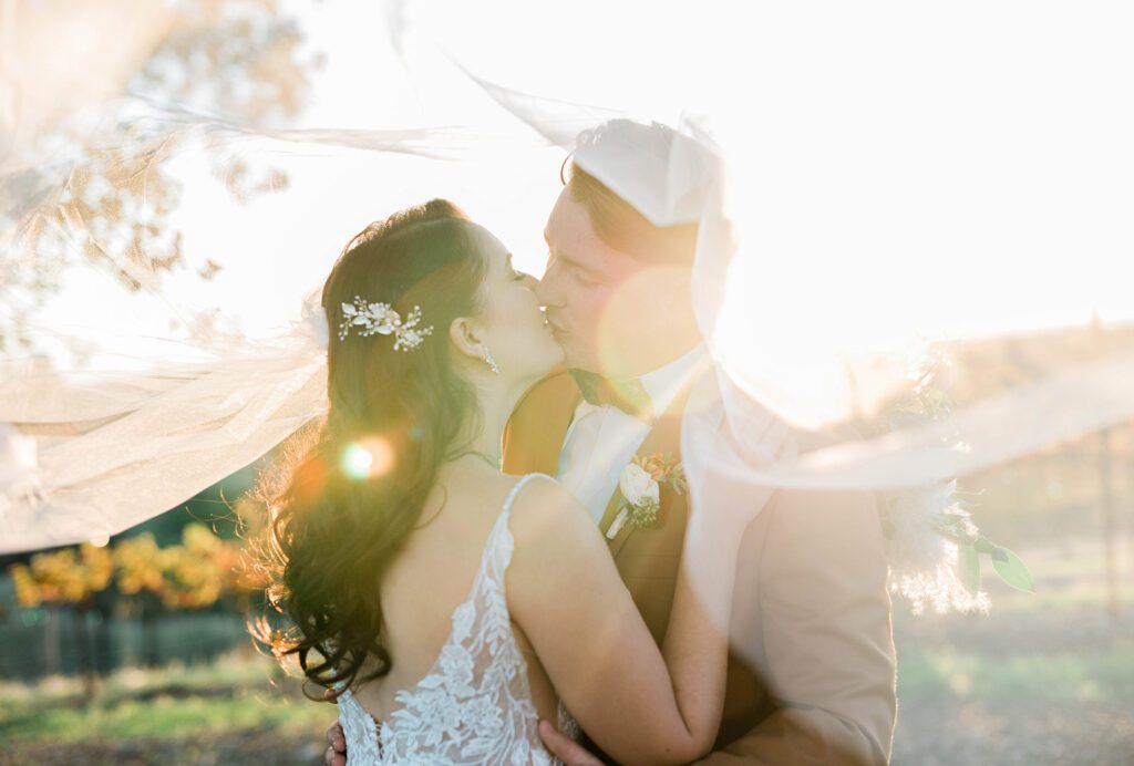 A bride and groom kiss in the sunset in a vineyard in Paso Robles during their Paso Robles Central Coast wedding day.