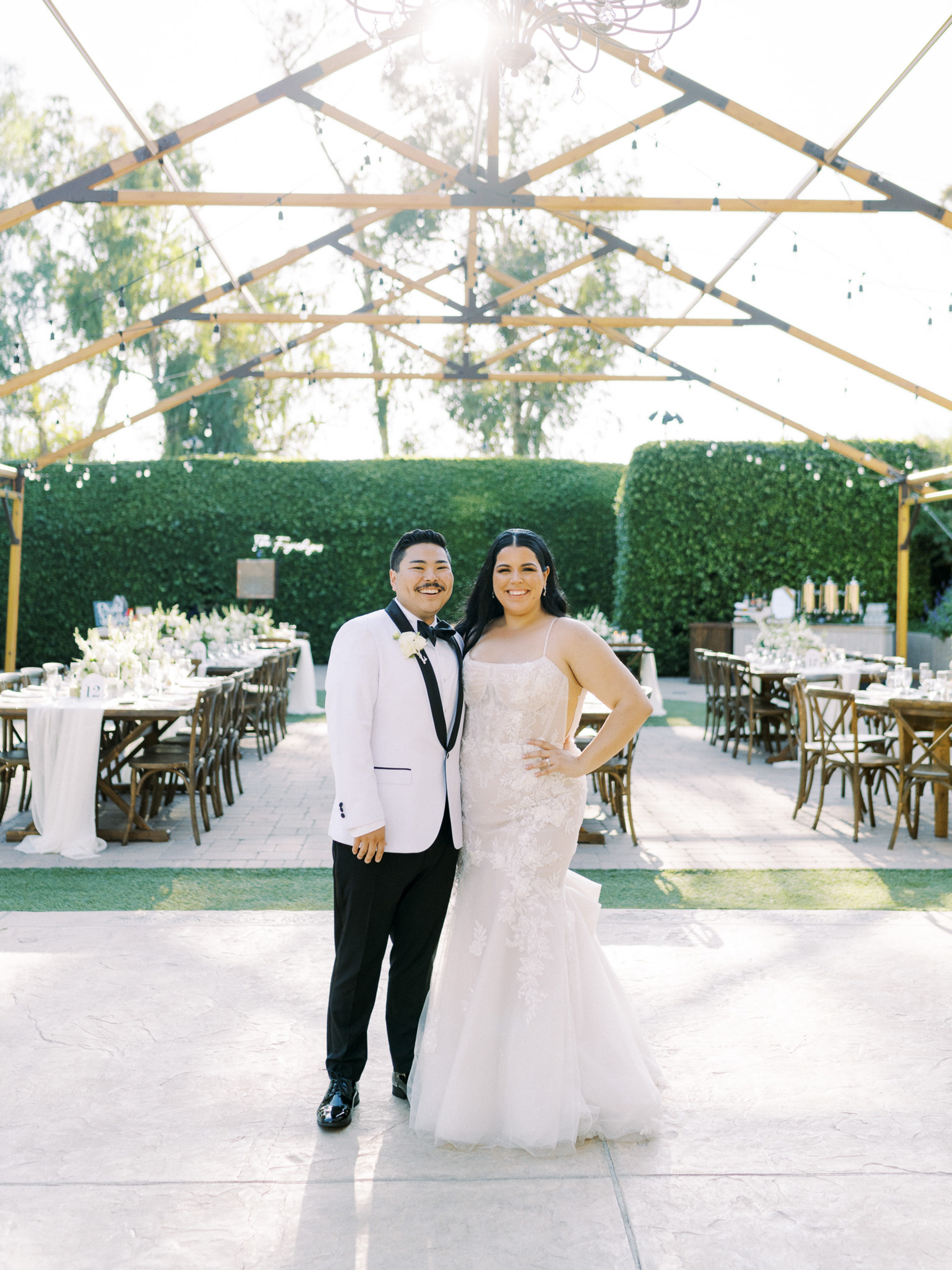 Newlyweds smiling at entrance of outdoor reception at Maravilla Gardens, Camarillo.

