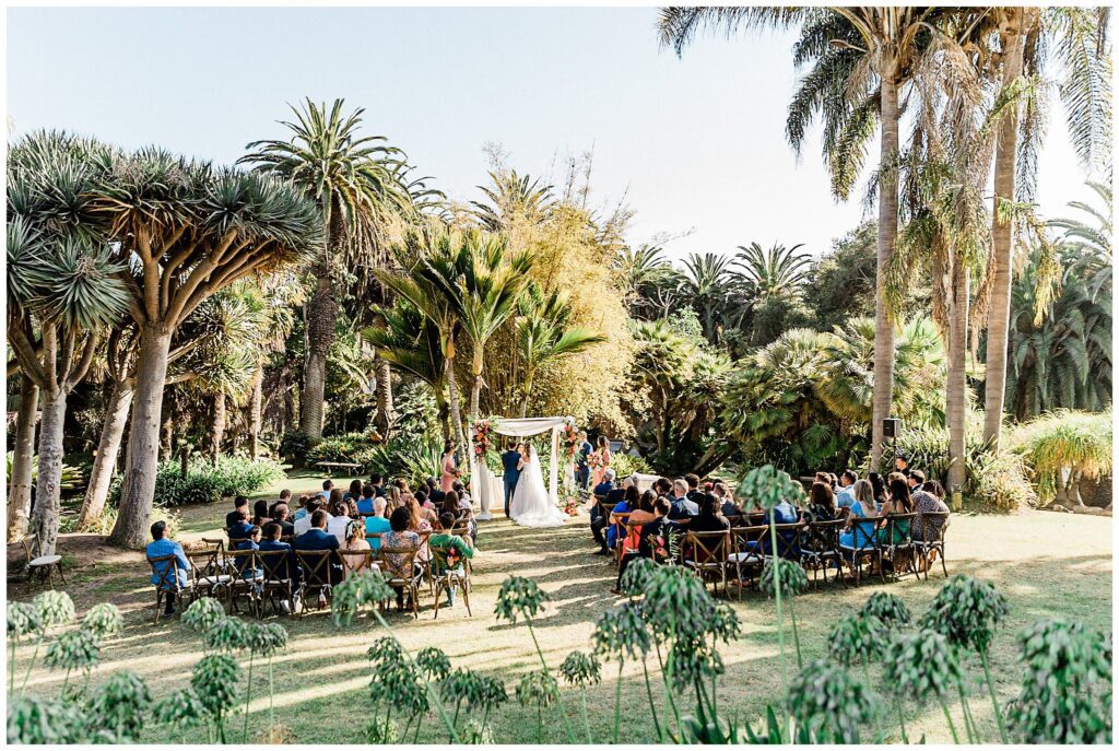 A wedding ceremony in the garden at the Santa Barbara zoo surrounded by botanical flowers.