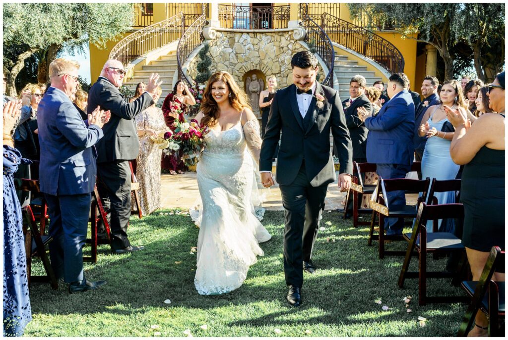 Bride and Groom exit the ceremony at Cali Paso winery, and Villa, laughing heavily as they hold hands during their Paso Robles Vineyard wedding day.