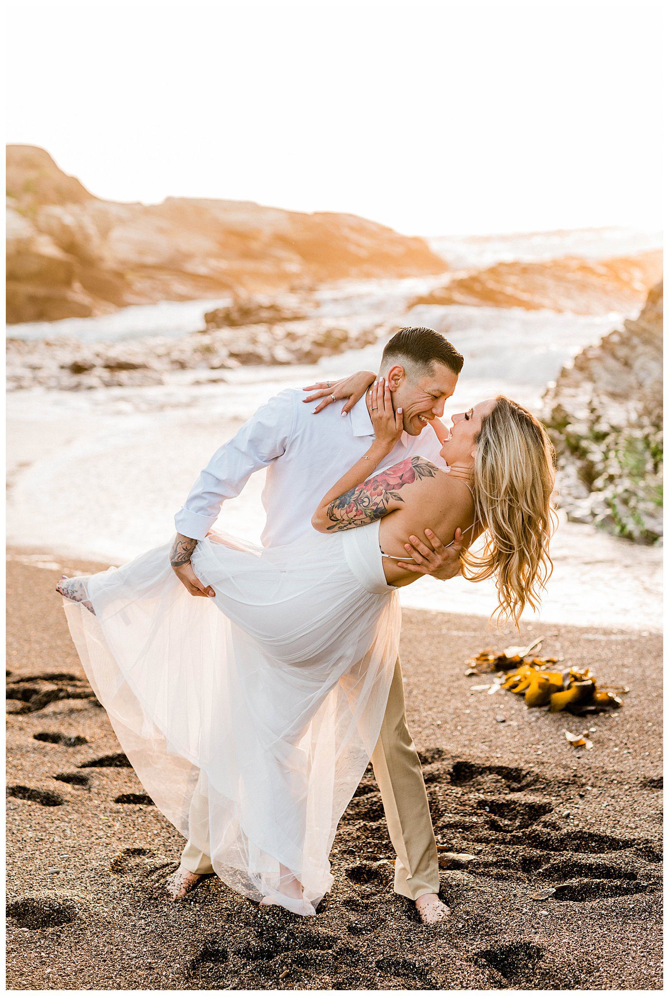 A bride and groom laugh during a candid moment on the beach while taking engagement session photos in Montana de Oro.