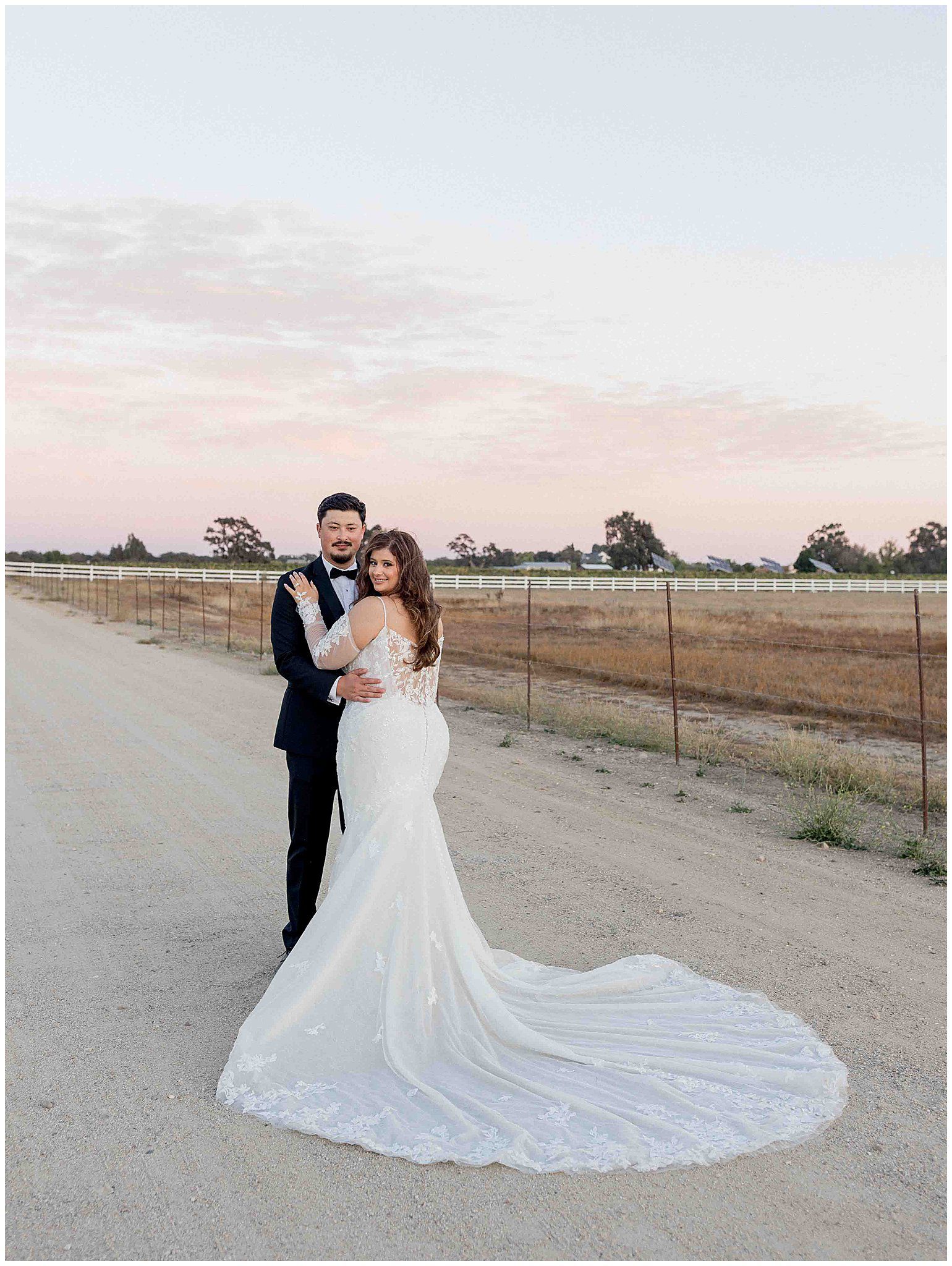 Bride and groom walking together in Paso Robles, with the bride’s train flowing beautifully in the background, captured by Leana Myra Photography.