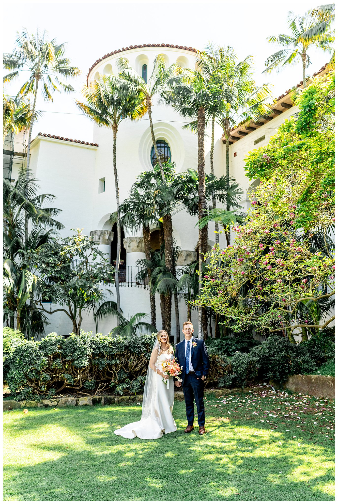 A bride and groom and wedding attire stand underneath the Spanish architecture at the Santa Barbara courthouse in the sunken Gardens on their wedding day.