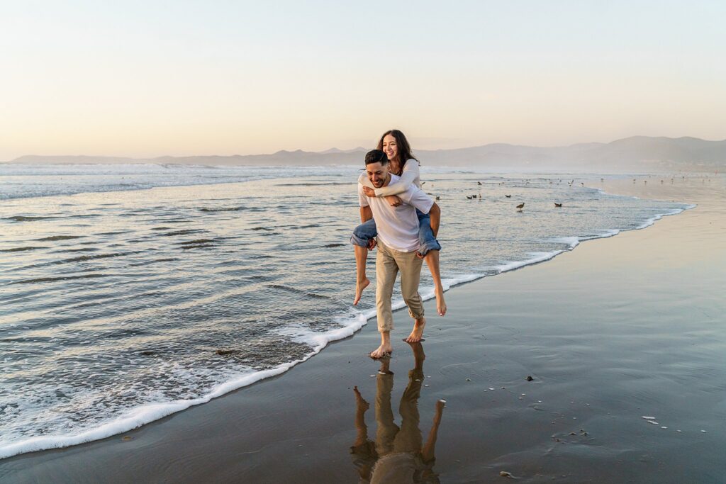 A couple frolics on the beach in morro bay for their engagement session on the central coast, while planning their wedding in paso robles. 