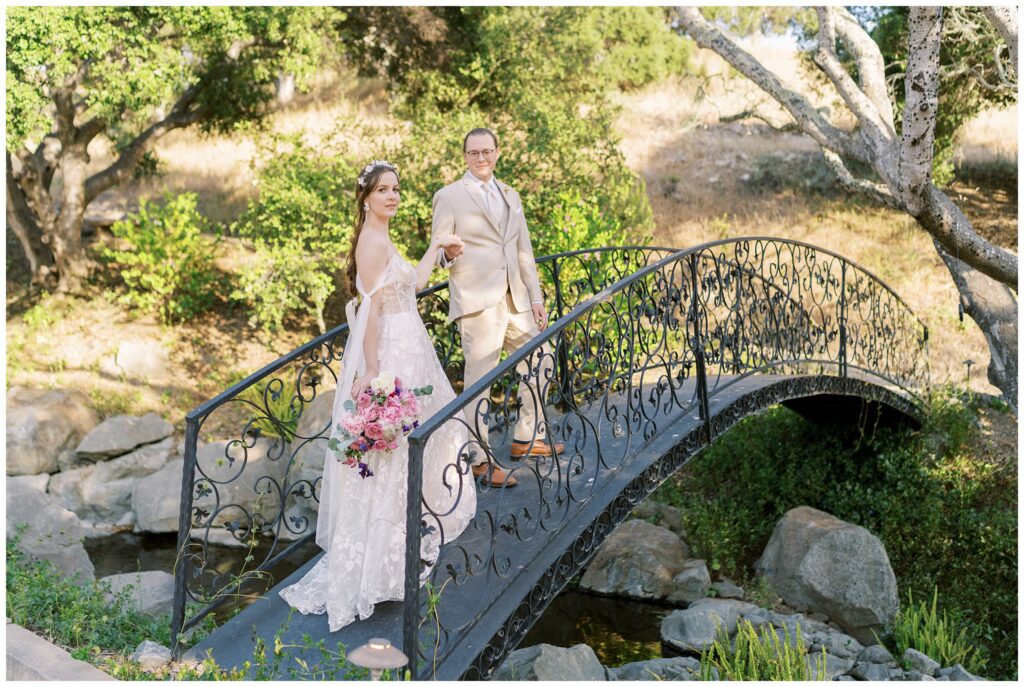 A romantic wedding at chateau Noland as the bride and groom cross over the bridge looking at the waterfall.