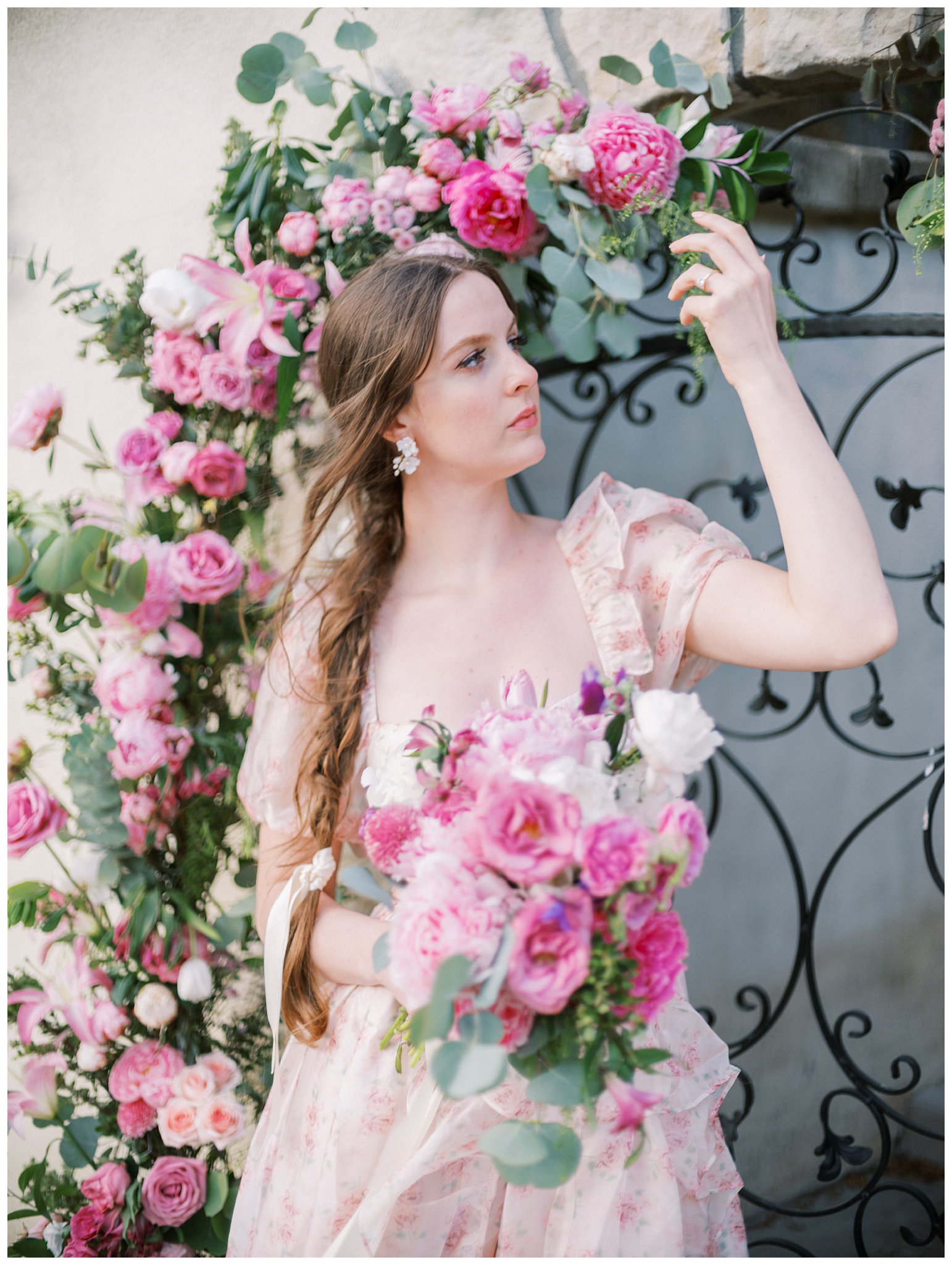 a woman holding flowers in front of a gate