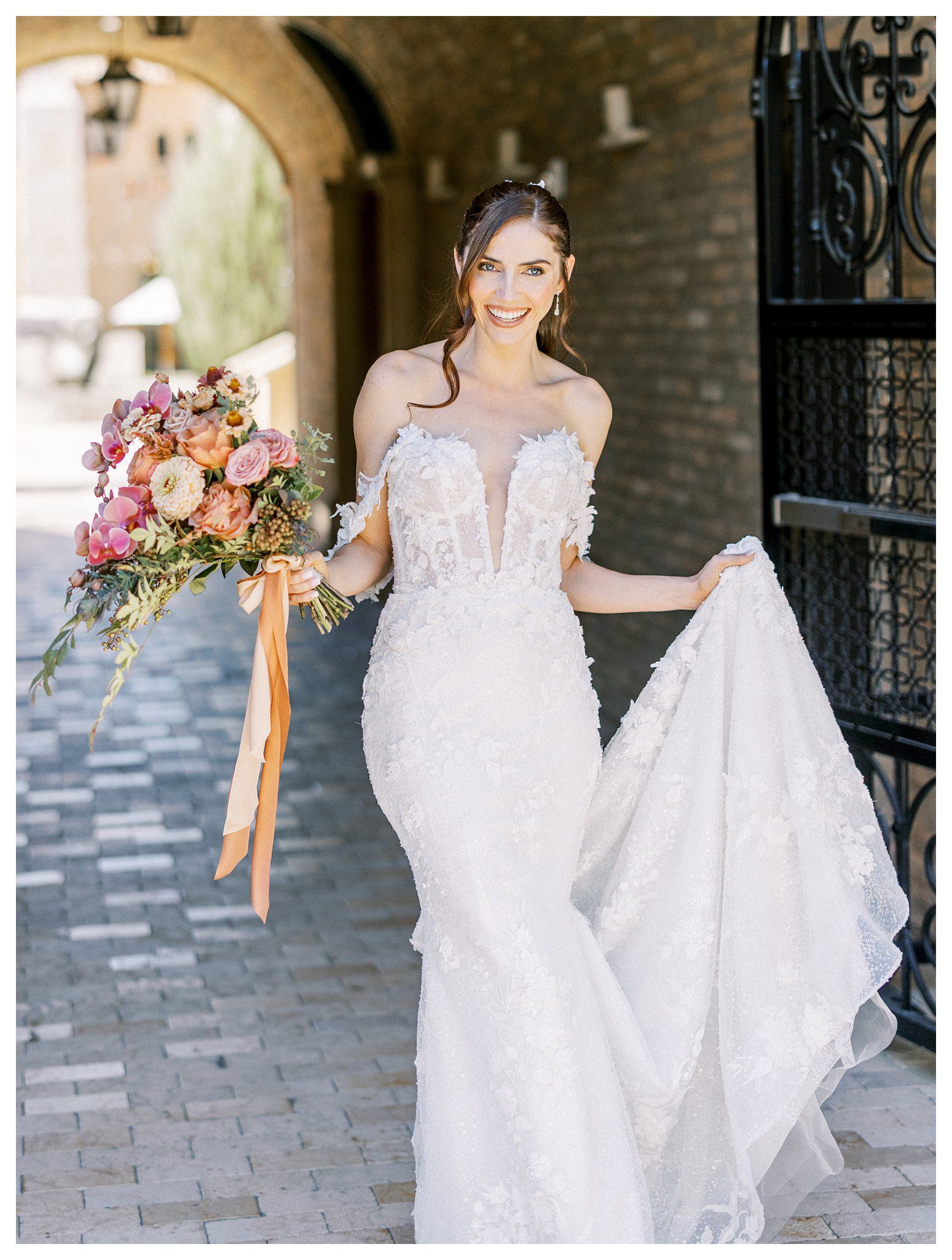Bride smiling with lace gown and floral bouquet at Allegretto