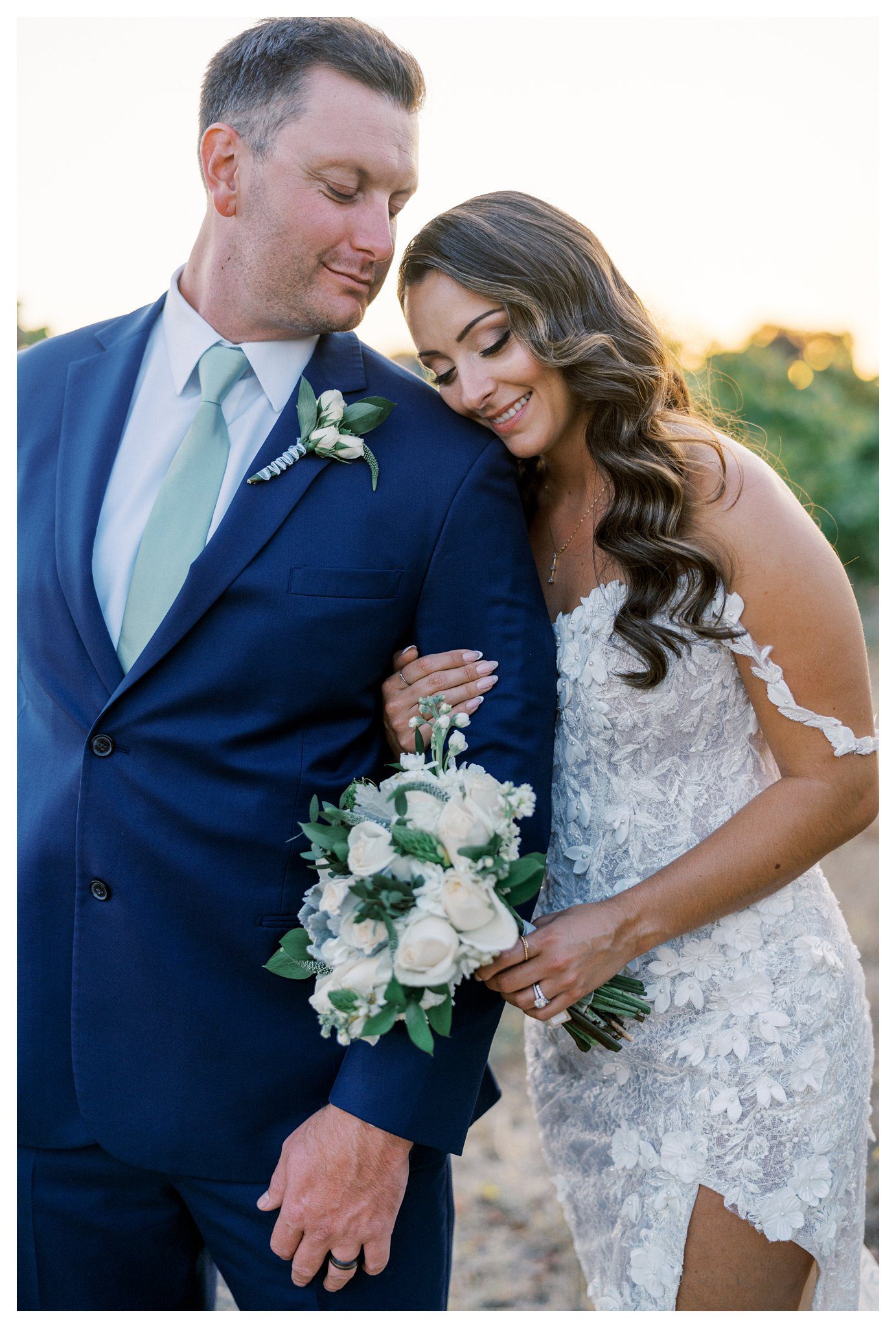 Sunset vineyard portrait of bride resting on groom’s shoulder