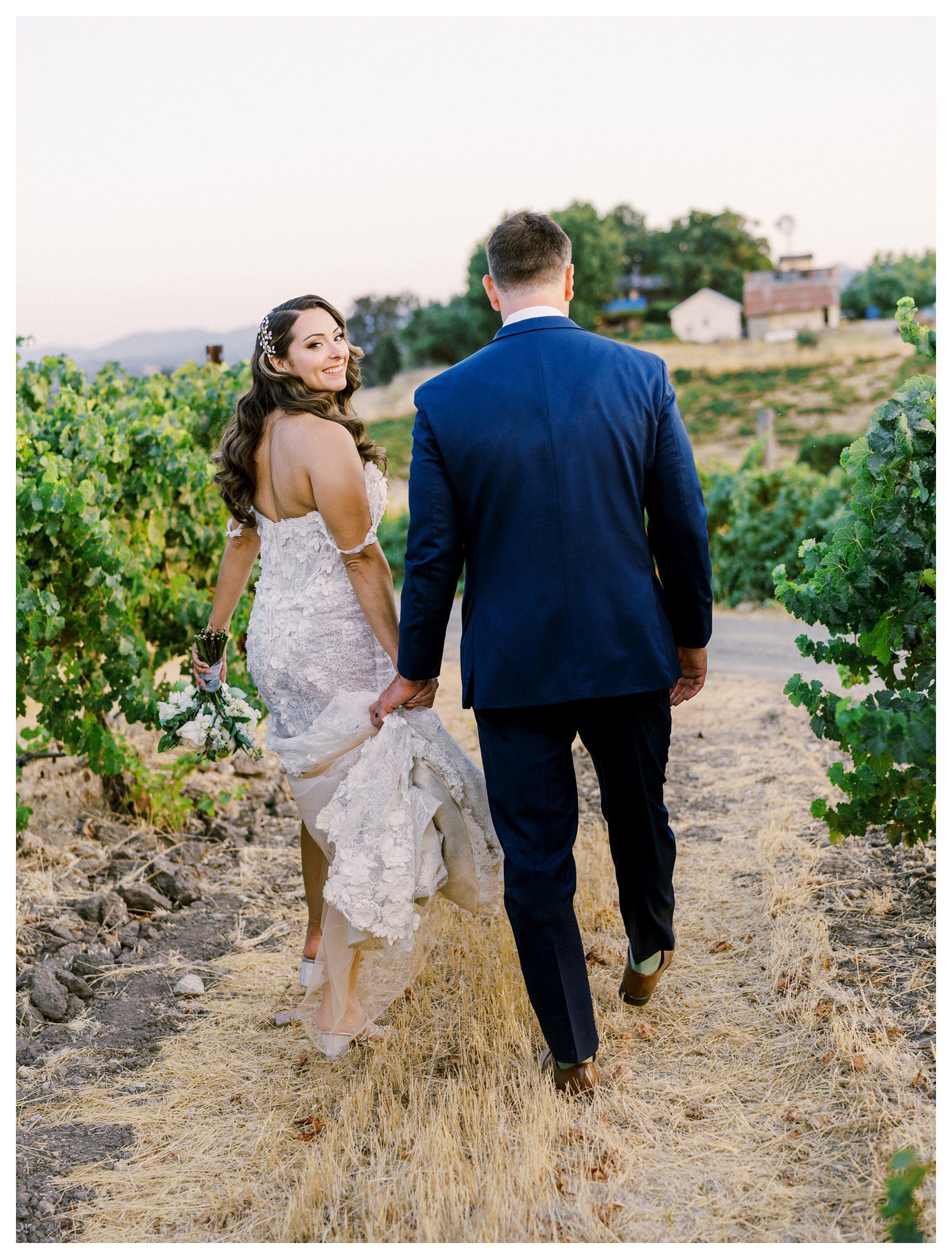 Bride and groom walking through vineyard at sunset in Paso Robles