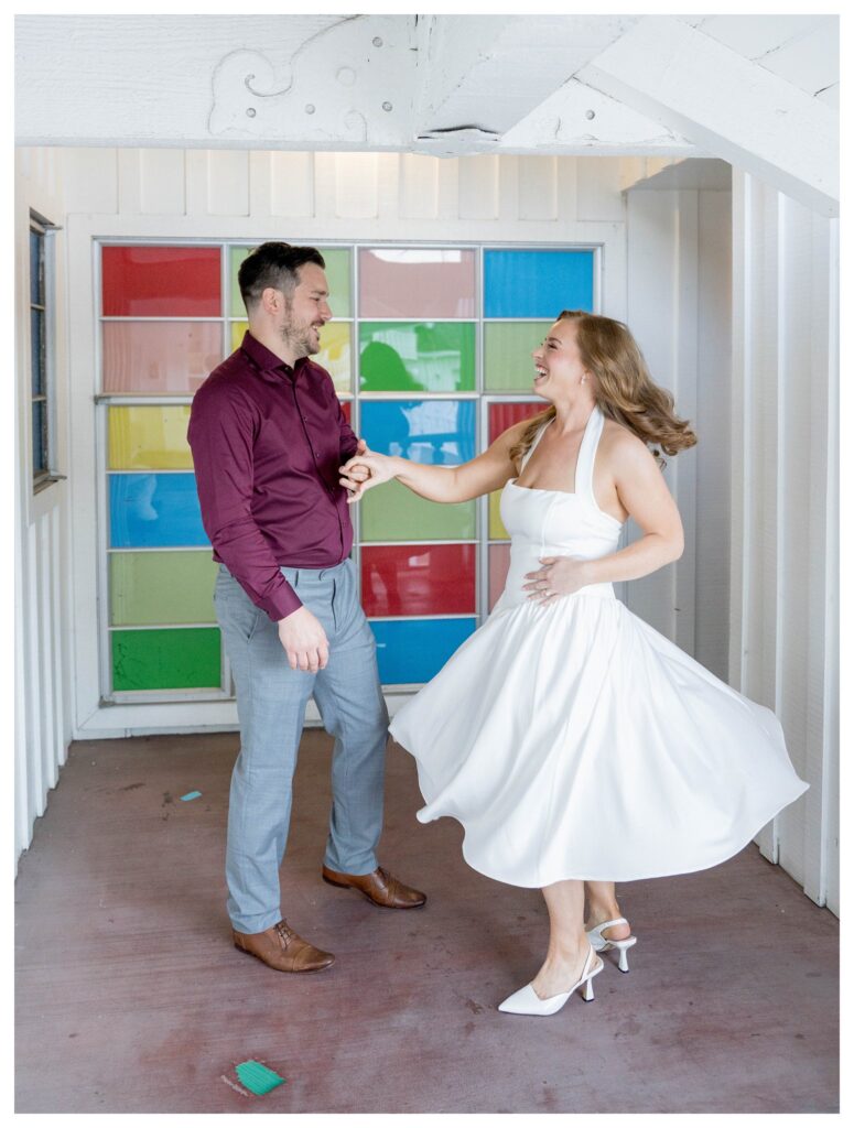Couple twirling by stained glass – Joyful Love | Madonna Inn Engagement | Leana Myra Photography