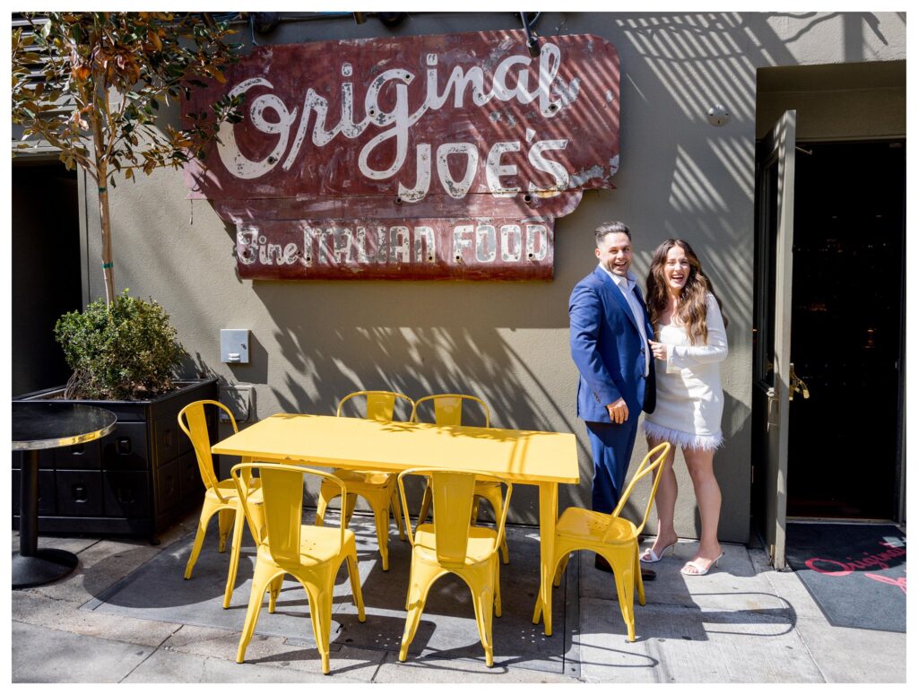 Man and woman laughing in front of original Joe's restaurant in San Francisco for their engagement session.