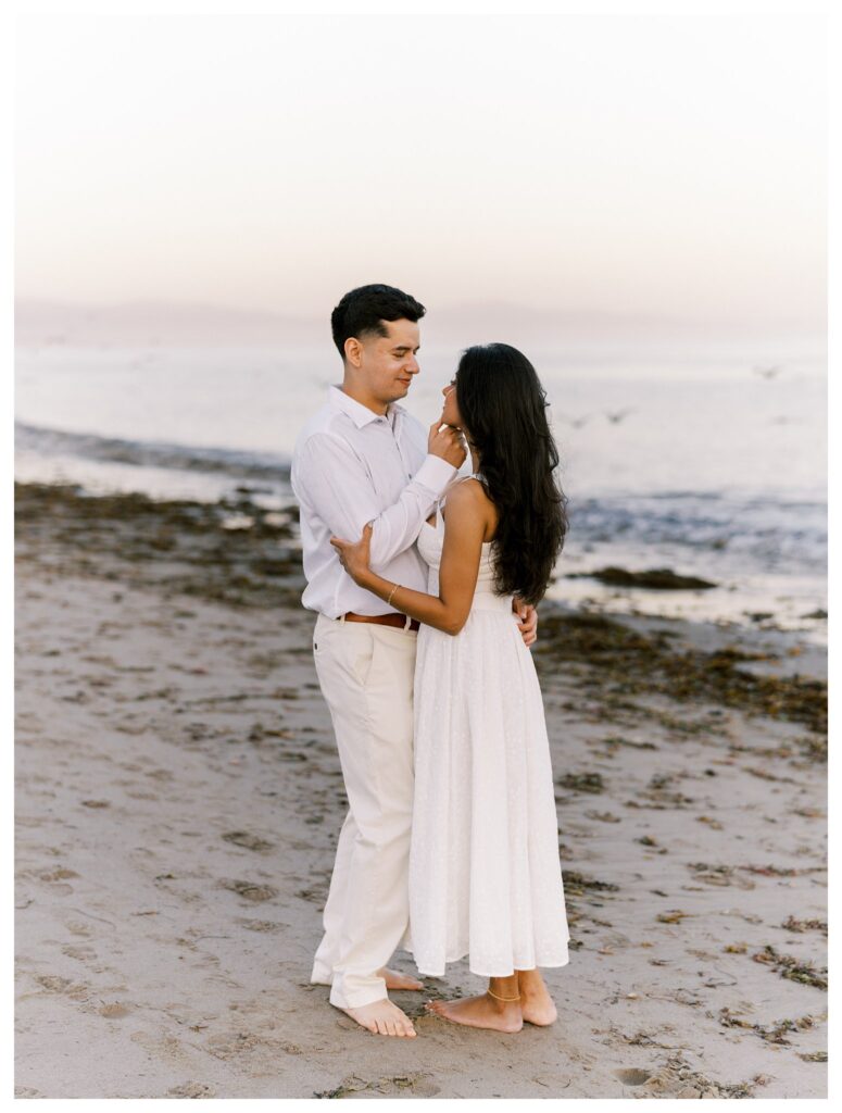 Couple barefoot on the sand at Leadbetter Beach during sunset, wrapped in a romantic embrace