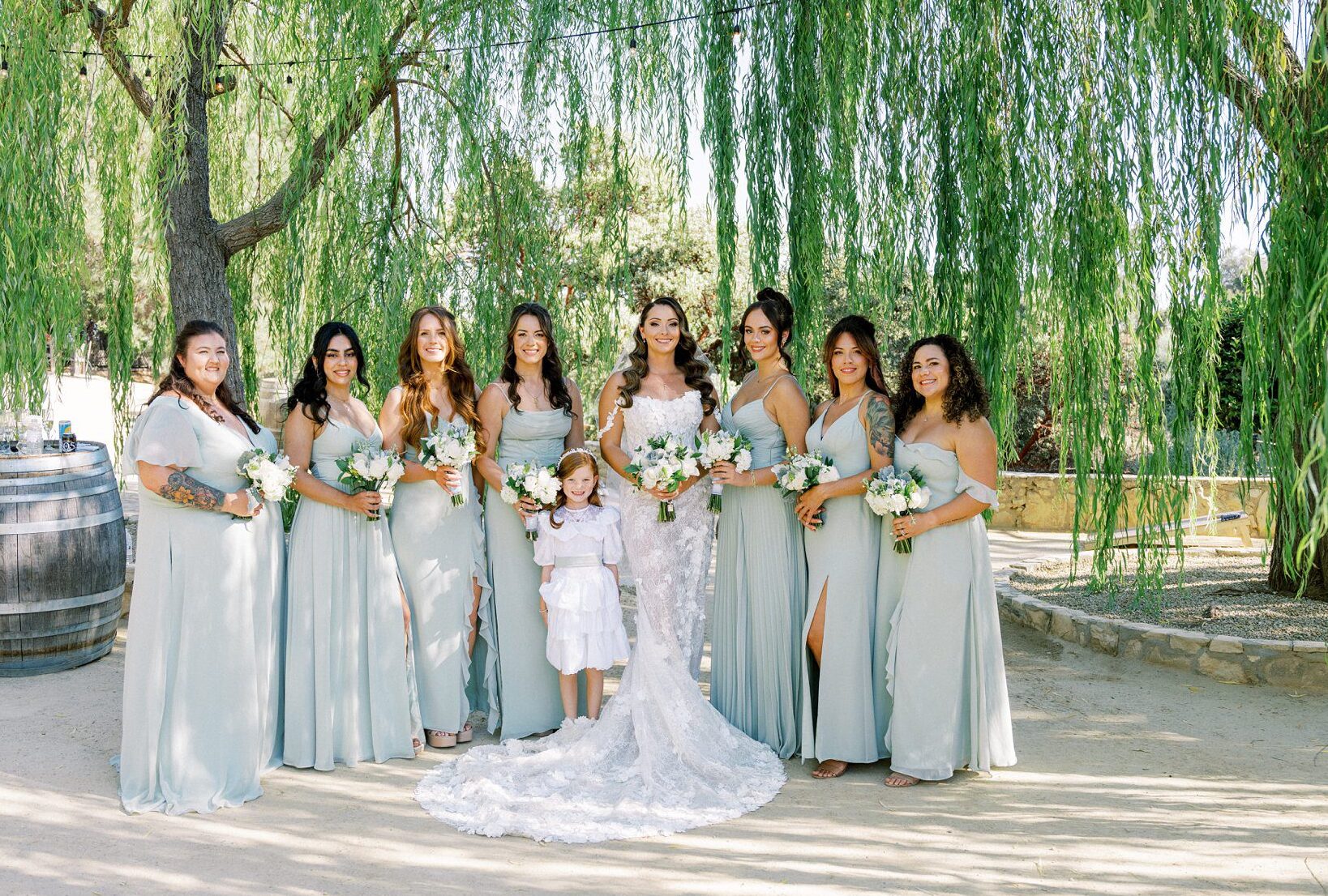 Full bridal party in sage green dresses with bride and flower girl