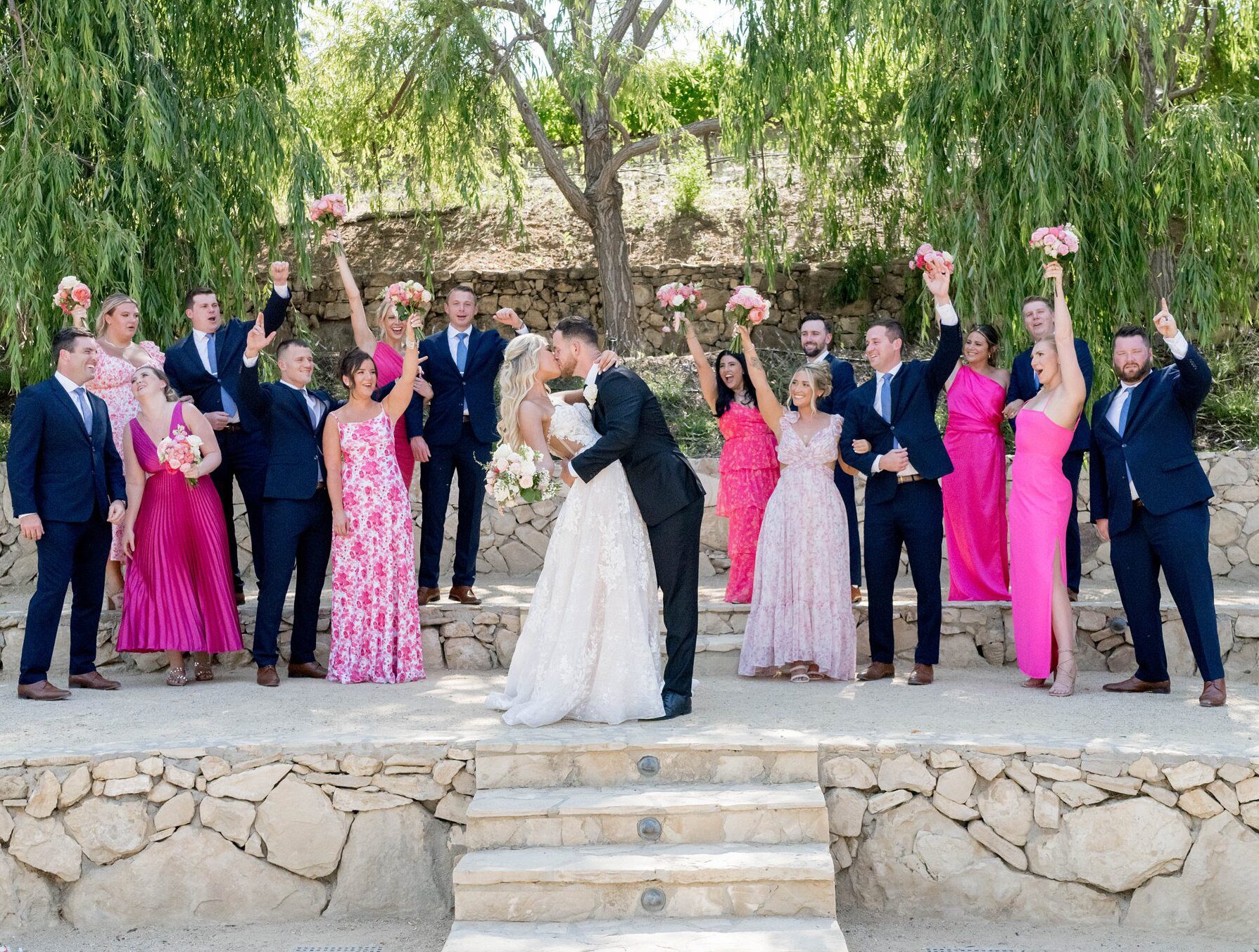 bridesmaids in hot pink dresses and groomsmen laughing during candid moment at terra mia vineyards